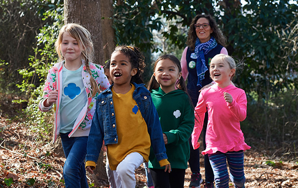 Group of Girl Scout Daisies hiking with adult volunteer