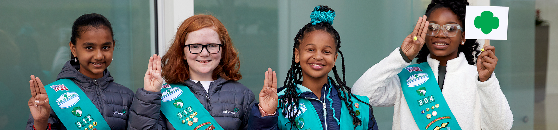  group of junior girl scouts displaying the girl scout sign with hands 