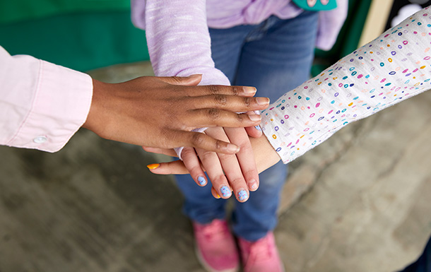 group of girl scouts with hands on top of each other